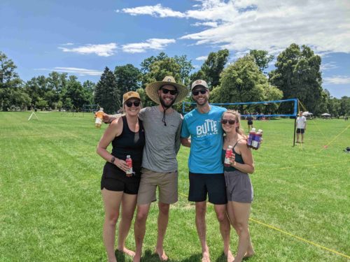 Friends holding Suja with volleyball court in background